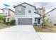 Two-story house with gray siding, gray garage door, and a blue front door at 16719 Delia St, Wimauma, FL 33598