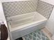 Clean, white bathtub with patterned tile surround for a refreshing bathing experience at 501 180Th E Ave, Redington Shores, FL 33708