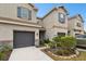 Tan three-story townhouse with gray garage doors and landscaping at 8126 Muddy Pines Pl, Tampa, FL 33635