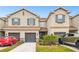Tan three-story townhouse with gray garage doors and landscaping at 8126 Muddy Pines Pl, Tampa, FL 33635