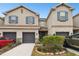 Tan three-story townhouse with gray garage doors and landscaping at 8126 Muddy Pines Pl, Tampa, FL 33635