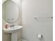 Clean and modern powder room with pedestal sink and circular mirror at 8126 Muddy Pines Pl, Tampa, FL 33635