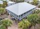 Elevated home with metal roof, screened porch, and brick paver driveway at 79 Palm Dr, Placida, FL 33946
