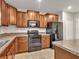 Modern kitchen with wood cabinets, granite countertops, and black appliances at 8506 Hunters Fork Loop, Ruskin, FL 33573