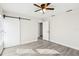 Bedroom with vinyl plank flooring, ceiling fan and barn door at 10904 90Th Ter, Seminole, FL 33772