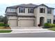 Two-story house with beige exterior, dark brown accents, and a three-car garage at 12854 Boggy Creek Dr, Riverview, FL 33579