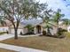 Tan house with a two-car garage, palm trees, and well-maintained landscaping at 1809 Citrus Orchard Way, Valrico, FL 33594