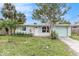 Ranch-style home with light brick exterior, teal garage door, and mature landscaping at 6702 Sandra Dr, Port Richey, FL 34668