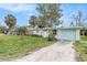 Front view of a ranch home with light brick, teal garage door, and palm trees at 6702 Sandra Dr, Port Richey, FL 34668