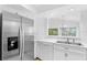 Stainless steel refrigerator in a white kitchen with a pass-through window at 15890 Sanctuary Dr, Tampa, FL 33647