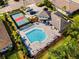 Aerial view of a community pool with lounge chairs, a tennis court, and lush landscaping at 19891 Bridgetown Loop, Venice, FL 34293