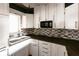 White kitchen cabinets, mosaic backsplash, and dark countertops at 2005 E Crenshaw St, Tampa, FL 33610