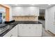White kitchen with black countertops and tile backsplash at 3939 Venetian Way, Tampa, FL 33634