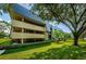 Modern condo building with lush landscaping and large shade tree at 36750 Us Highway 19 # 21-301, Palm Harbor, FL 34684