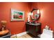 Stylish powder room with dark vanity, round mirror, and an orange accent wall at 930 Monterey Ne Pt, St Petersburg, FL 33704