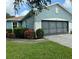Front view of a single-story house with a two-car garage and lush landscaping at 1213 Huntington Greens Dr, Sun City Center, FL 33573