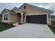 Tan house with a brown garage door and landscaped yard at 13278 Ogden Glade Rd, Dade City, FL 33525