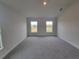 Spacious bedroom with grey carpet and two large windows at 13290 Ogden Glade Rd, Dade City, FL 33525