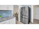 Stainless steel refrigerator in a modern kitchen with white cabinets and granite countertops at 1613 Heather Pl, Palm Harbor, FL 34684