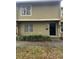 Tan two-story townhome with black door, landscaping, and sidewalk at 7638 Woodbridge Blvd, Tampa, FL 33615