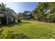 Large backyard with tropical landscaping, spacious lawn, and a detached shed at 8755 Commodore Dr, Seminole, FL 33776