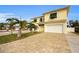 Two-story house with a yellow facade, white garage doors, and palm trees at 11325 5Th E St, Treasure Island, FL 33706