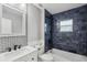 Bathroom with dark blue tile shower, white vanity, and patterned mirror at 126 90Th Ave, Treasure Island, FL 33706