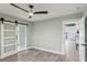 Light and bright bedroom with wood-look floors, barn door, and ceiling fan at 126 90Th Ave, Treasure Island, FL 33706