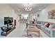 Bright living room with sectional sofa, large TV, and view into kitchen at 15618 Aurora Lake Cir, Wimauma, FL 33598