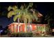 Two-story house with palm trees and landscape lighting at night at 710 Islebay Dr, Apollo Beach, FL 33572