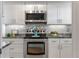 Modern white kitchen with stainless steel appliances and granite countertops at 131 Bluff View Dr # 103, Belleair Bluffs, FL 33770