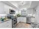 Modern white kitchen with stainless steel appliances and granite countertops at 131 Bluff View Dr # 103, Belleair Bluffs, FL 33770