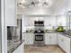 Modern white kitchen with stainless steel appliances and granite countertops at 131 Bluff View Dr # 103, Belleair Bluffs, FL 33770