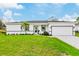 White house with gray roof, paved driveway, and green lawn at 189 Statler St, Port Charlotte, FL 33954