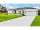 White house with gray roof, paved driveway, and grassy yard at 189 Statler St, Port Charlotte, FL 33954