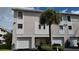 Two-story condo building with attached garages, landscaping, and palm trees at 255 Capri N Cir # 17, Treasure Island, FL 33706