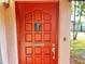 Close-up of the red front door featuring a decorative glass insert and a brushed metal handle at 6700 Turner N St, St Petersburg, FL 33702