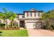 Two-story house with a two-car garage, palm trees, and manicured lawn at 19510 Whispering Brook Dr, Tampa, FL 33647