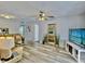 Open living room with hardwood floors, ceiling fan, and large TV at 8651 10Th N St # 130, St Petersburg, FL 33702