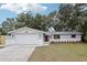Newly renovated home with gray and white exterior, landscaped yard, and a two-car garage at 11592 110Th Ter, Seminole, FL 33778