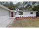 Newly renovated home with gray and white exterior, landscaped yard, and a red door at 11592 110Th Ter, Seminole, FL 33778