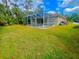 Home's backyard features a screened pool and grassy lawn at 4293 Shrimp Ln, North Port, FL 34286