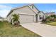 Tan house with a two-car garage and a neatly landscaped lawn at 17019 Avon Dive Ln, Wimauma, FL 33598
