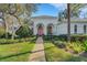 White house with pink door, landscaped yard, and walkway at 2850 Deer Run, Tarpon Springs, FL 34688
