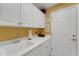 Bright laundry room with white cabinets and a large utility sink at 2850 Deer Run, Tarpon Springs, FL 34688