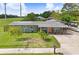 Charming single-story home featuring well-manicured lawn, mature trees, and a lovely pink door at 442 Country Club Dr, Oldsmar, FL 34677