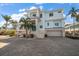 Two-story waterfront home with light blue exterior, palm trees, and brick driveway at 477 20Th Ave, Indian Rocks Beach, FL 33785