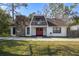 A charming A-frame house with a red door and stone chimney at 705 Whiteway Dr, Brooksville, FL 34601