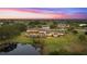 Aerial view of a luxurious estate home with spacious backyard, scenic pond, and covered lanai at dusk at 12405 Stonelake Ranch Blvd, Thonotosassa, FL 33592