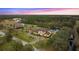 Aerial twilight view showcasing estate home amidst wooded acreage, manicured lawns, and a private pond at 12405 Stonelake Ranch Blvd, Thonotosassa, FL 33592